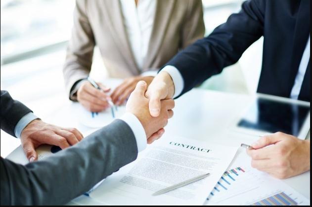 Two parties shaking hands over a signed engagement contract