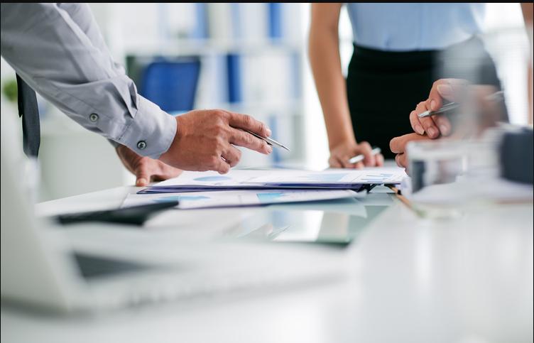 Two consultants reviewing compliance documents at a desk