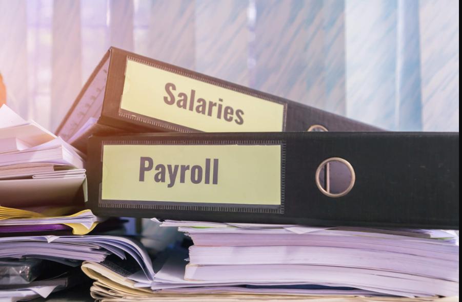 Salary and payroll record files stacked on a desk